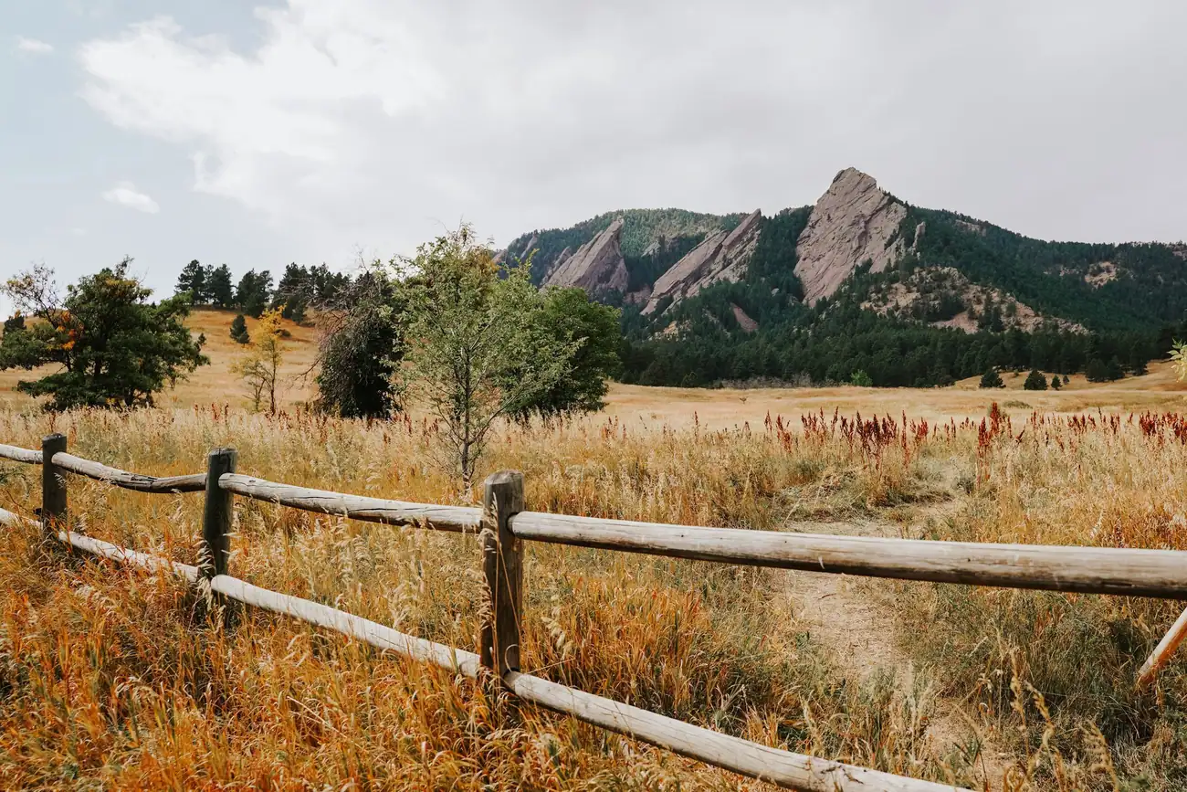 The Flatirons above a rail fence and grassland at the edge of Boulder, CO