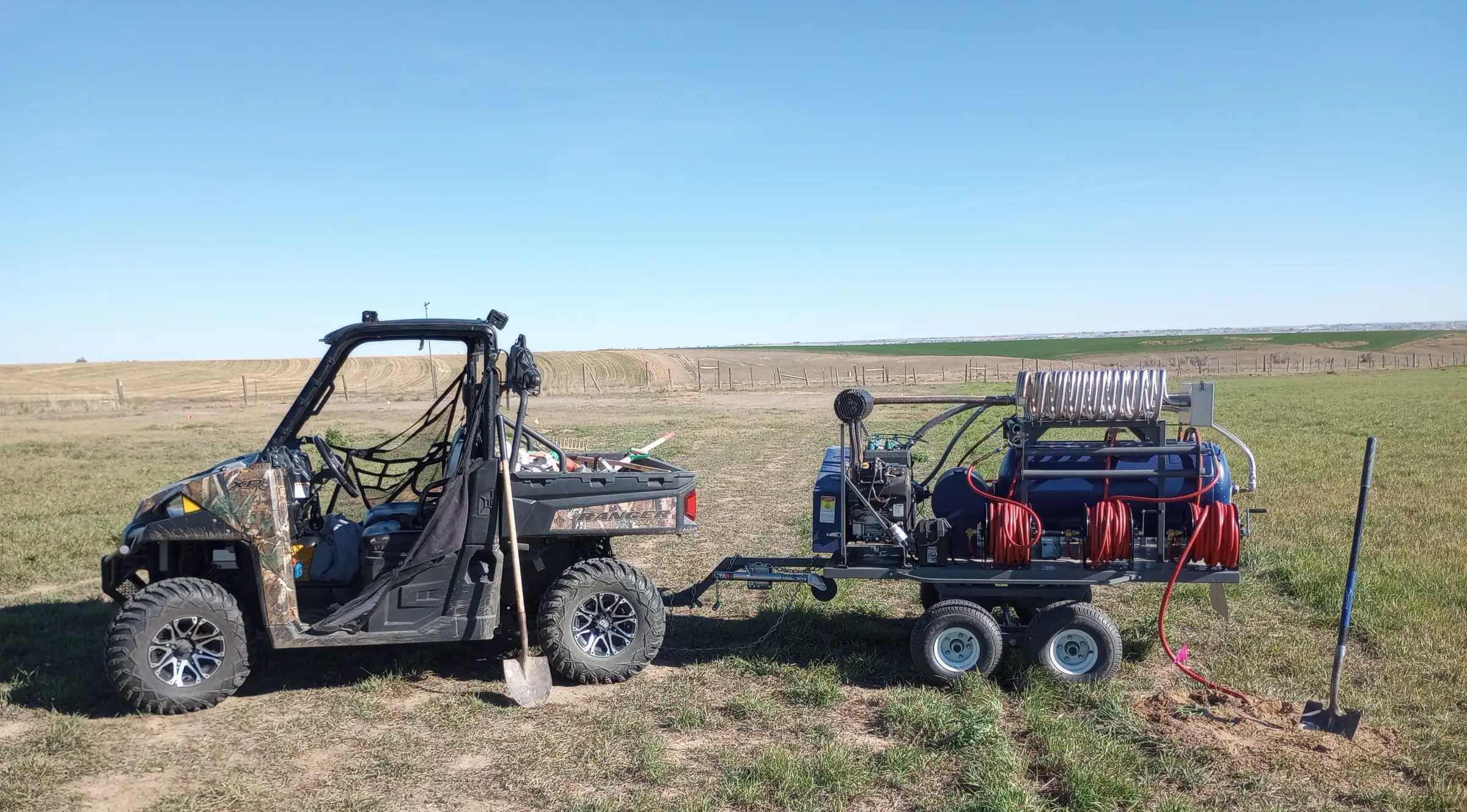The Rodent Ranger’s UTV towing the PERC rig across a prairie dog colony under a big Colorado sky